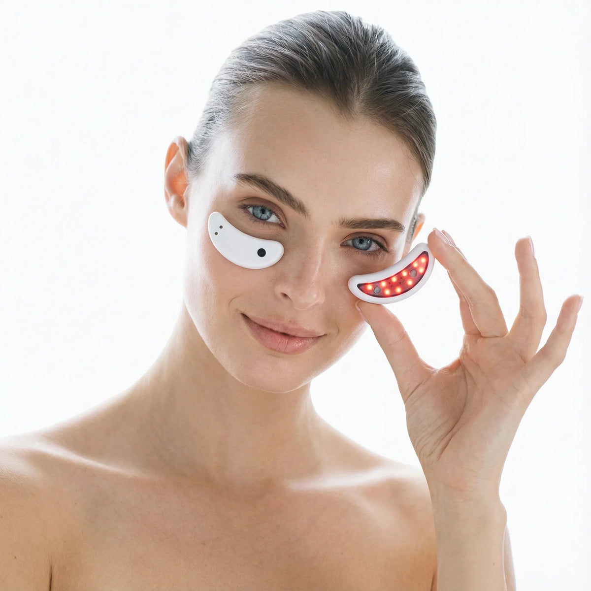 Woman placing a glowing Nicebeam Red Light Therapy Eye Pod under her eye