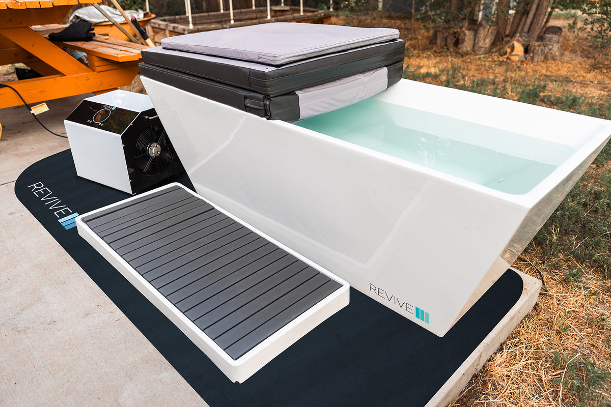 Padded protective mat positioned beside a Revive cold plunge