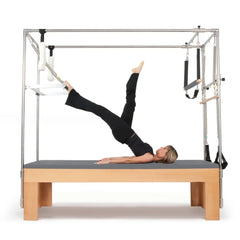Woman performing a leg lift exercise on the grey Elina Pilates Wooden Cadillac