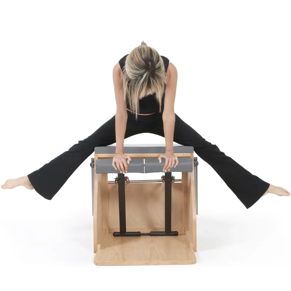 Woman using the gray Elina Pilates wooden base Combo Chair in a front facing exercise