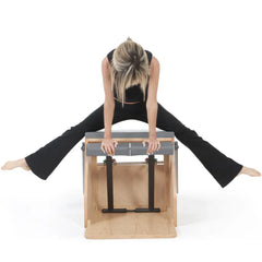 Woman using the gray Elina Pilates wooden base Combo Chair in a front facing exercise