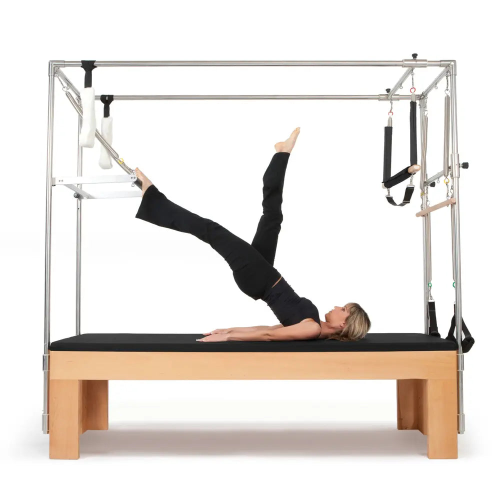 Woman performing a leg lift exercise on the black Elina Pilates Wooden Cadillac
