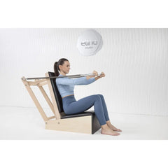Woman performing a seated arm exercise on the Elina Pilates Baby Chair