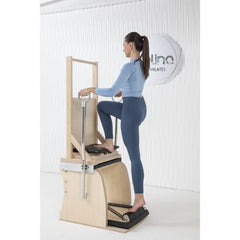 Woman performing a supported standing exercise on the Elina Pilates Wunda Electric Chair