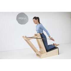 Woman performing a standing arm exercise with the Elina Pilates Baby Chair