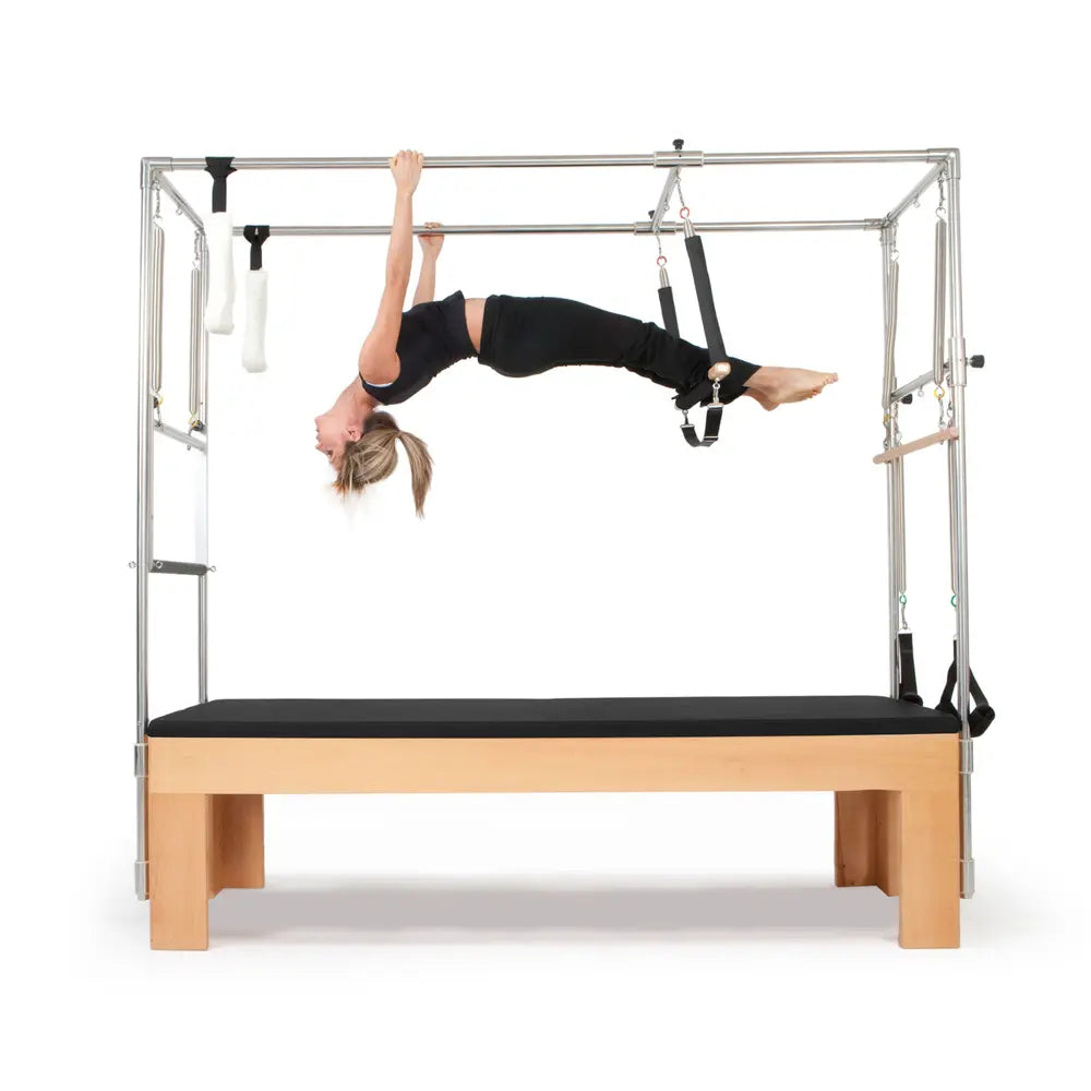 Woman performing a hanging exercise on the black Elina Pilates Wooden Cadillac