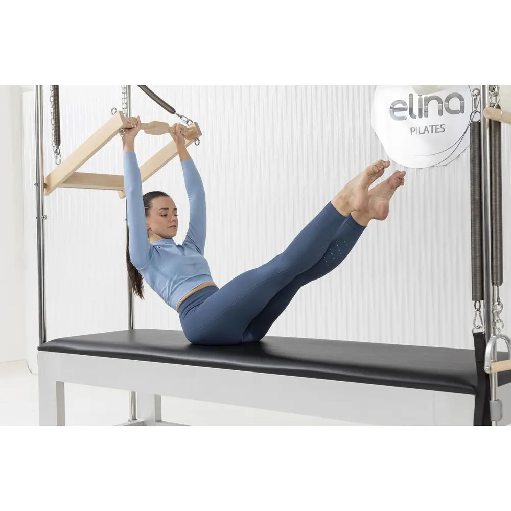 Woman performing a roll-back exercise on the Elina Pilates Classic Aluminum Cadillac