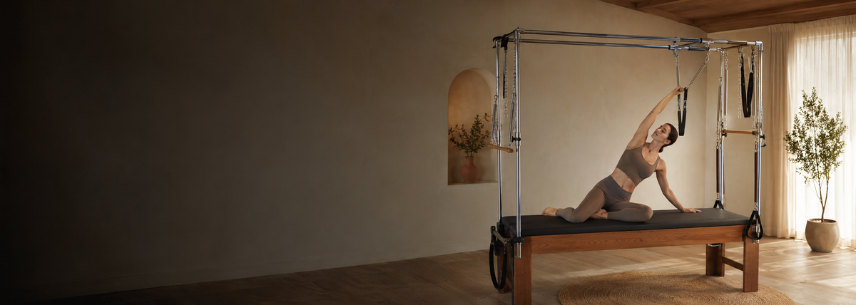 Woman stretching on a Pilates Cadillac in a warm home studio