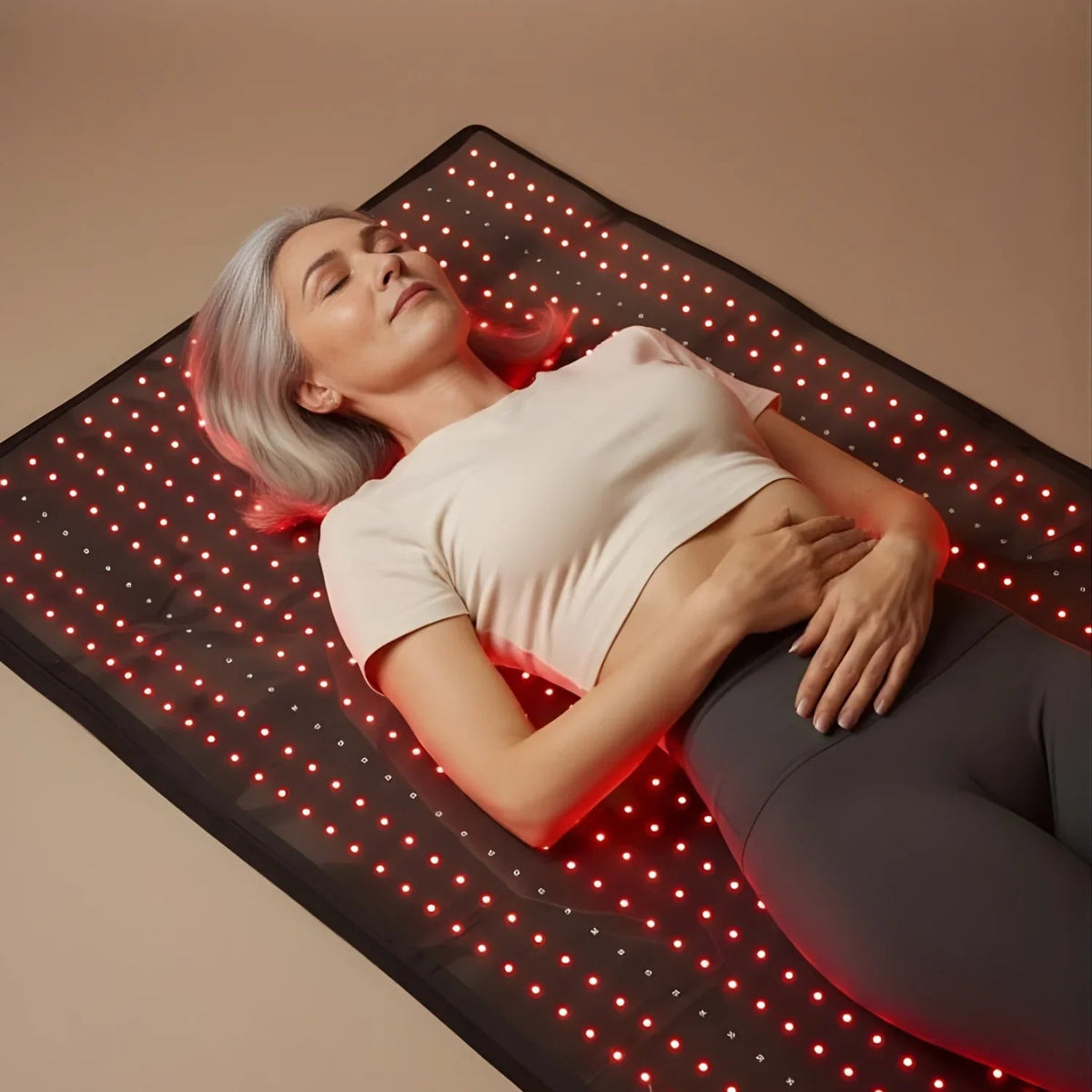 Woman lying on the illuminated Nicebeam full body red light therapy mat