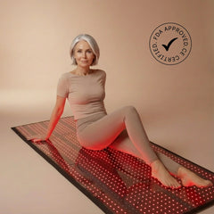 Woman sitting on the illuminated Nicebeam full body red light therapy mat