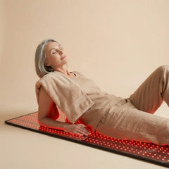 Woman relaxing while seated on the Nicebeam red light therapy mat