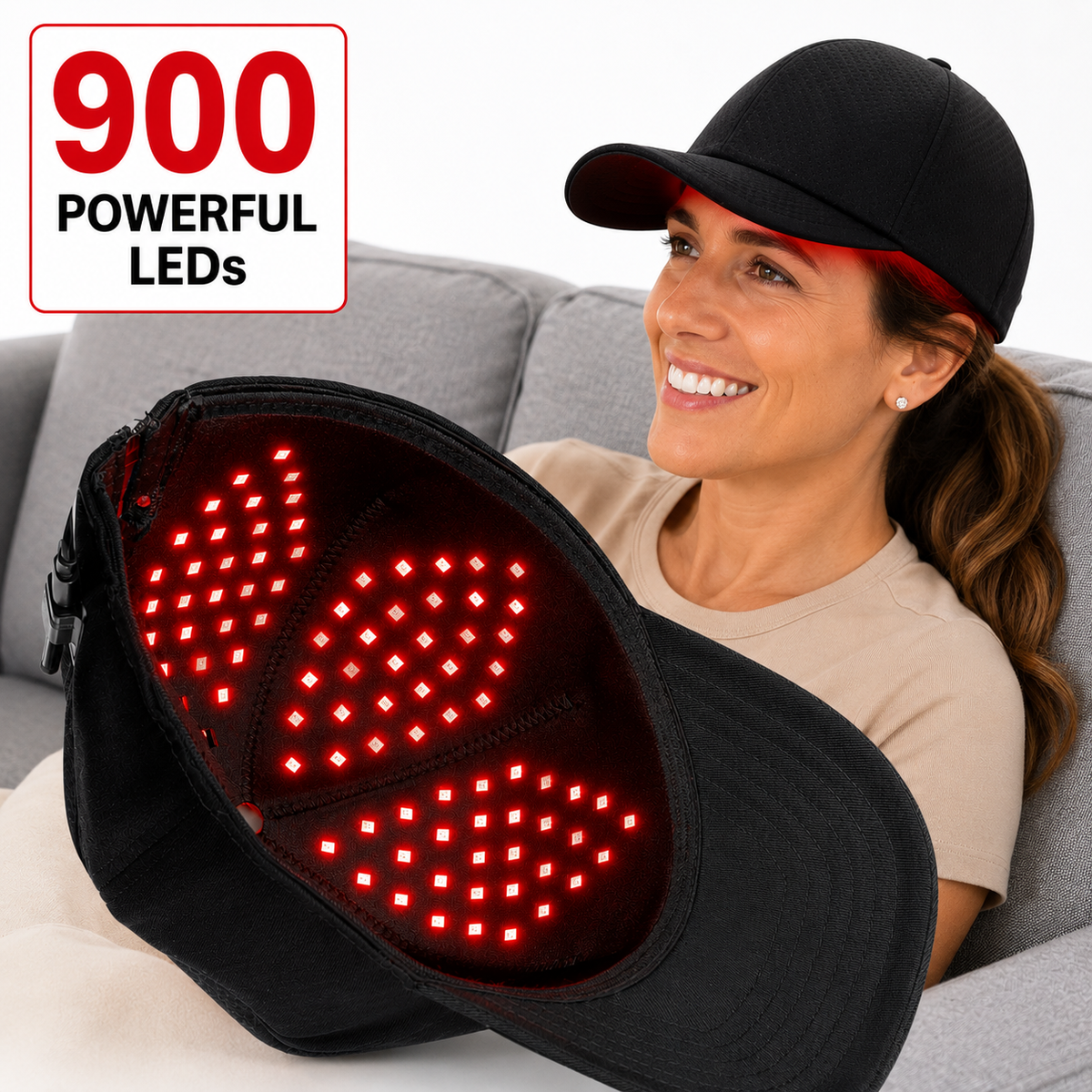 Woman seated on a sofa holding the illuminated Red Light Pro Devices 900 LED therapy hat