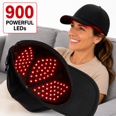 Woman seated on a sofa holding the illuminated Red Light Pro Devices 900 LED therapy hat