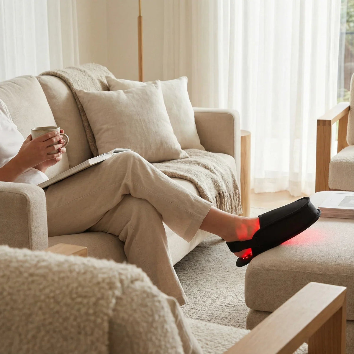 Woman relaxing on a sofa wearing Nicebeam red light therapy slippers