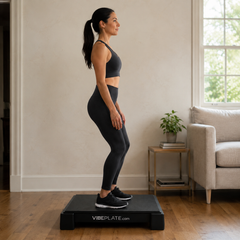 Woman using the VibePlate 2424 whole-body vibration platform at home