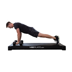 Man performing a dumbbell push-up on the VibePlate XL platform