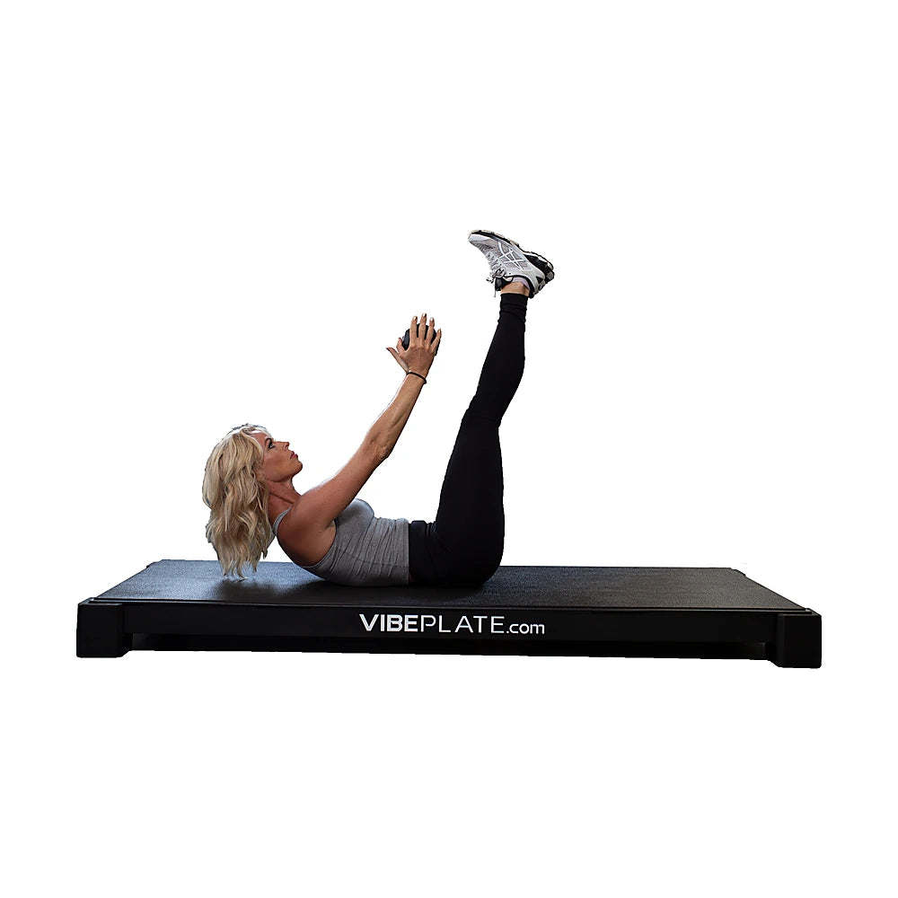 Woman performing a lying leg raise on the VibePlate XL platform