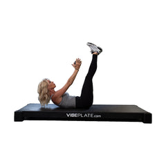 Woman performing a lying leg raise on the VibePlate XL platform