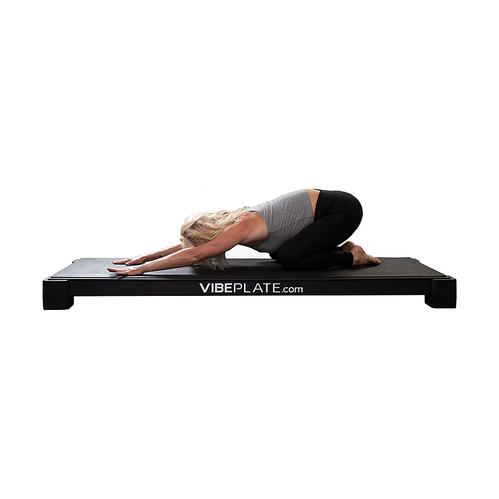Woman performing a child pose stretch on the YogaPlate vibration platform